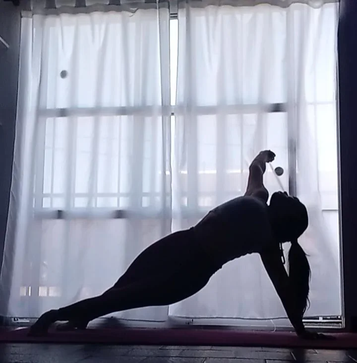 Práctica de yoga en silueta frente a cortinas