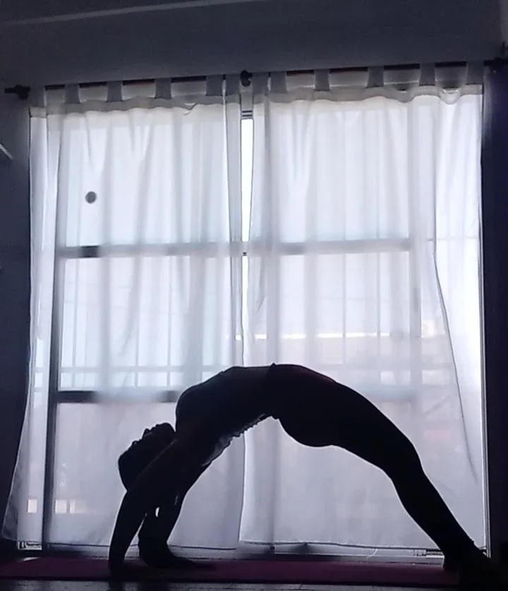 Postura de yoga en puente frente a una ventana